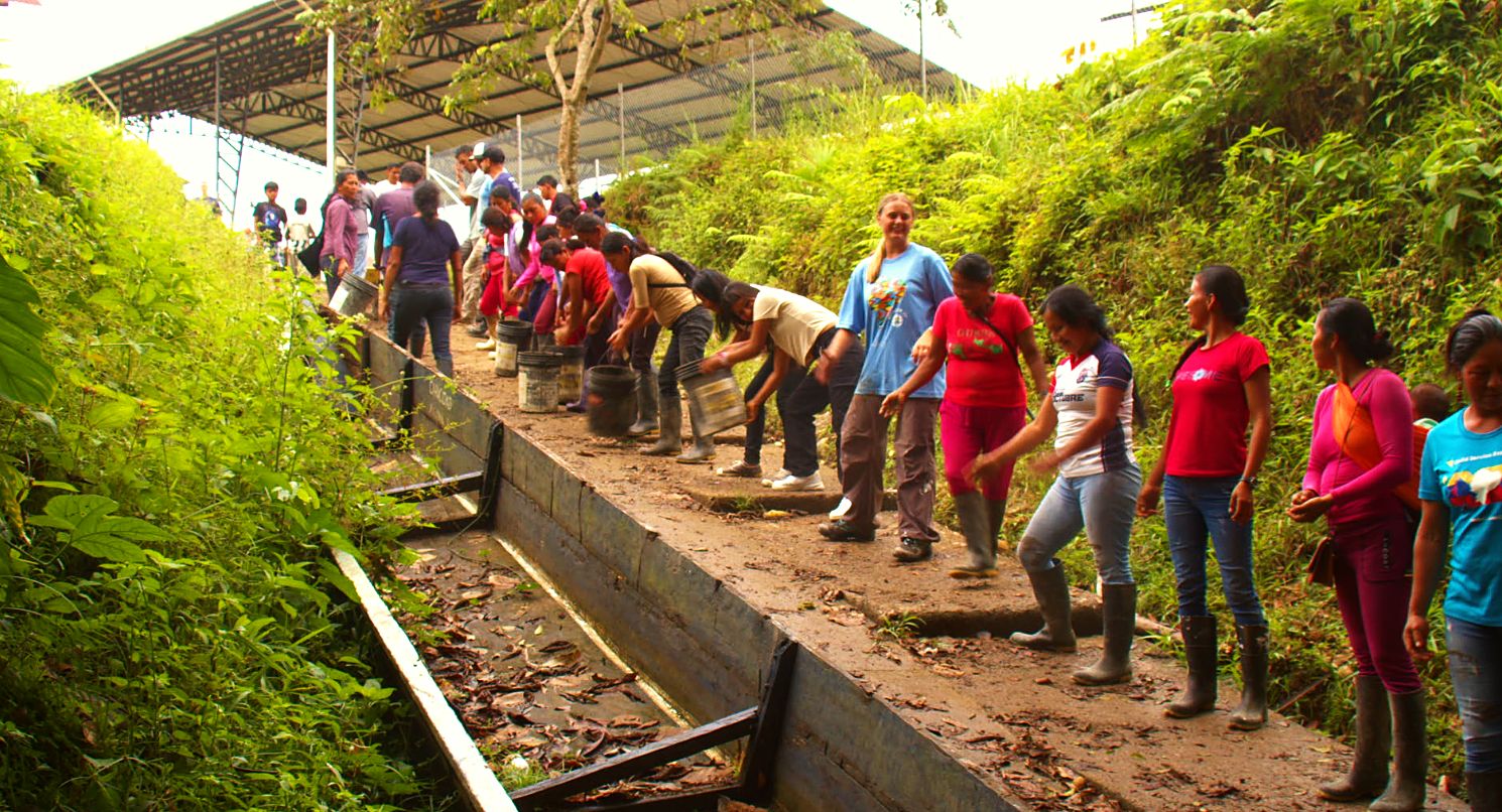 A long line of villagers and volunteers passing buckets of concrete down the hillside