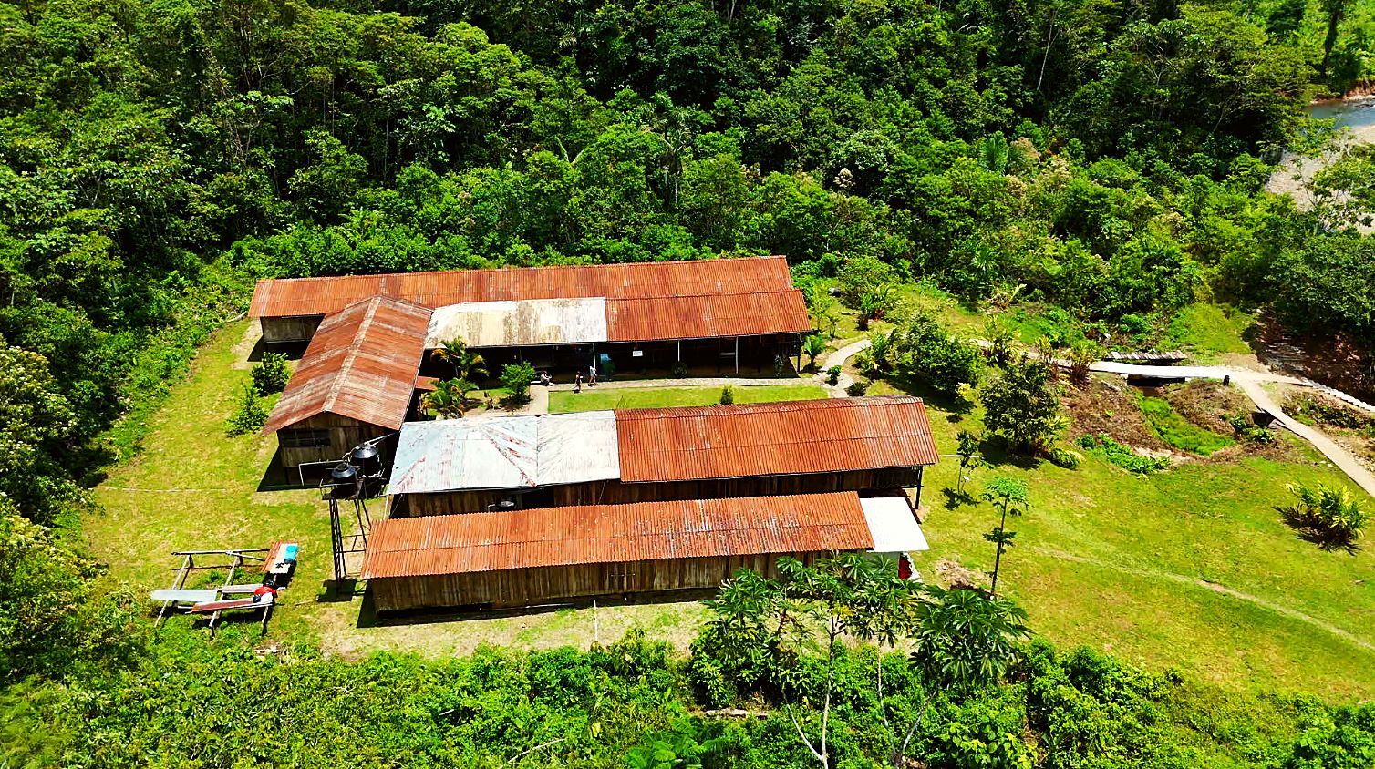 Base camp from above, its rust-red roofs surrounded by forest