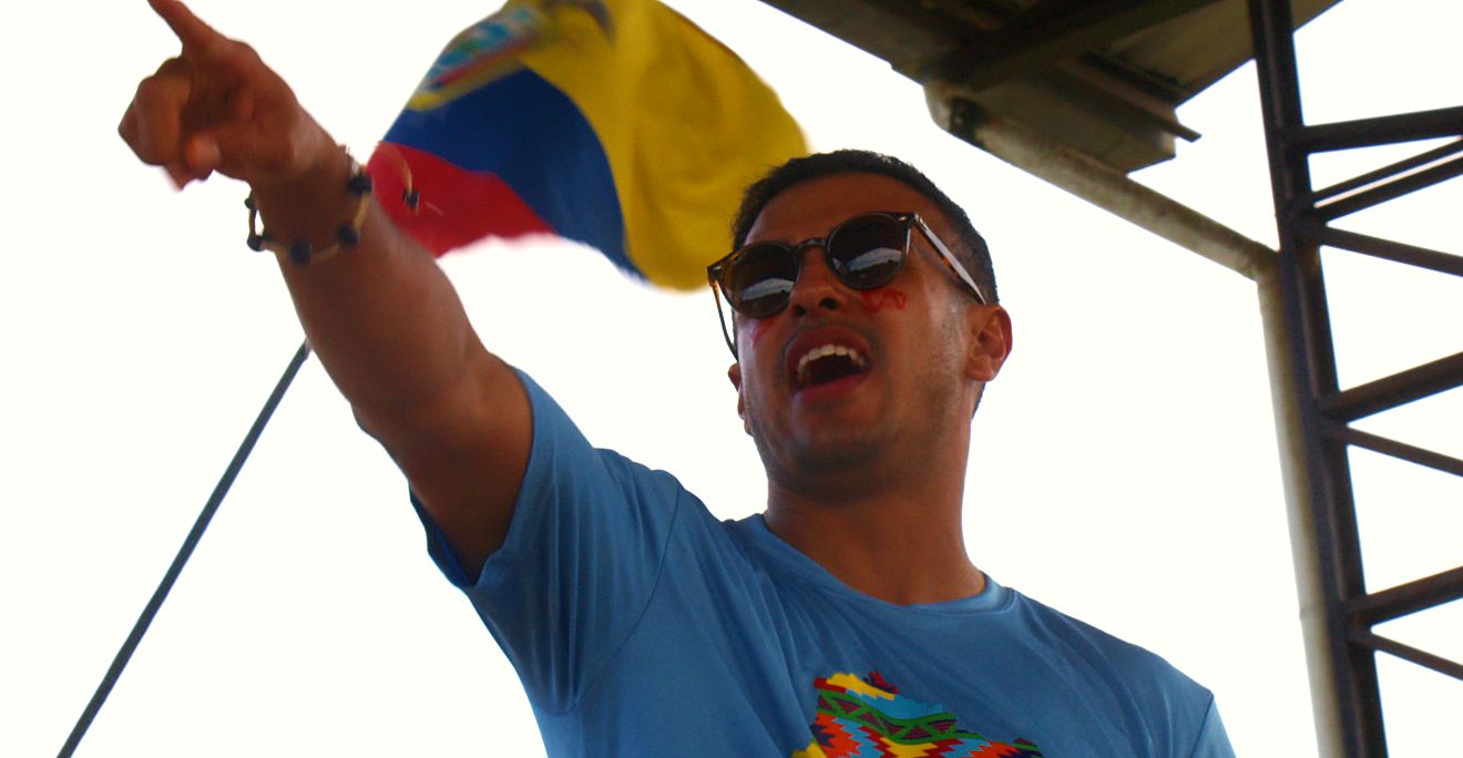 A volunteer pointing beneath the Ecuadorian flag