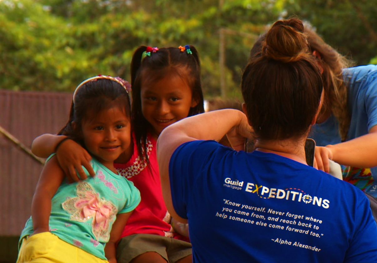 Two girls posing beside a volunteer in a team shirt